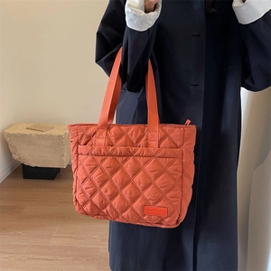 Detail der orangefarbenen Stepptasche mit Rautenmuster und weicher Stofftextur