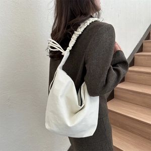 Détail du sac à bandoulière en toile blanche avec bretelles à volants et cordons de serrage