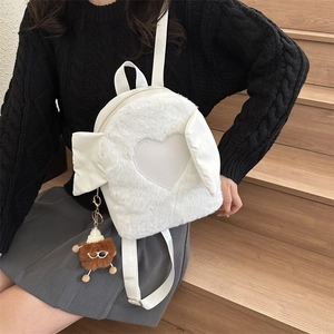 Detailed view of white plush backpack featuring heart patch, wings, and brown bear pendant