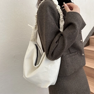 Détail d'un sac à bandoulière en toile blanche avec bandoulière à volants et zip noir