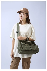 Detail of army green canvas messenger bag with large front pockets and wide strap