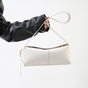 Dettaglio di una borsa a tracolla bianca in pelle con cuciture verticali e fibbia dorata