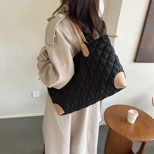 Détail d'un grand sac cabas noir matelassé avec des anses beiges contrastées