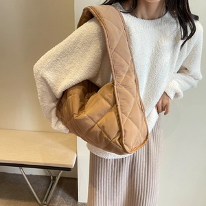 Close-up of quilted tan puffer shoulder bag with soft padded straps on a fashion model
