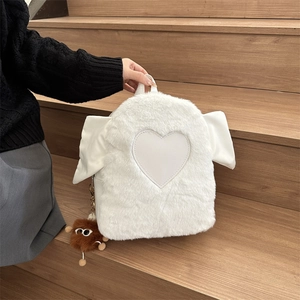 Close-up of fluffy white plush backpack with leather heart patch and wings on a wooden stair