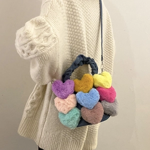 Détail d'un sac en peluche patchwork en forme de cœur avec poignée en denim sur pull