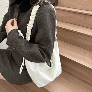 Détail latéral d'un sac en toile blanc cassé avec une bandoulière froncée style scrunchie