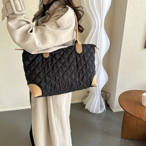 Détail du sac cabas matelassé noir avec coins et bandoulière en cuir beige clair