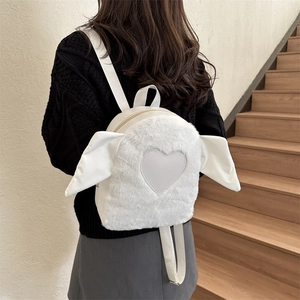 Macro detail of the white plush mini backpack featuring heart patch and wing decorations