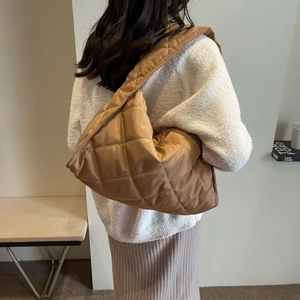 Detailed macro view of caramel quilted nylon shoulder bag with oversized crescent silhouette