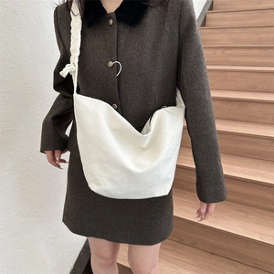 Détail d'un sac bandoulière en toile blanche avec nœud unique sur la sangle de style minimaliste