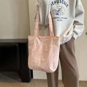 Close-up of pink nylon tote bag showing soft fabric texture and minimal shoulder strap design