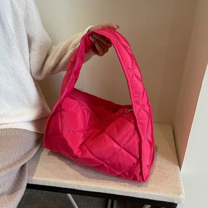 Detail of rose red quilted puffer tote bag in soft nylon fabric with wide shoulder strap