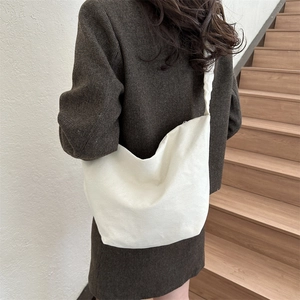 Sac bandoulière en toile blanche minimaliste porté sur un manteau pour un look d'hiver