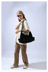 Detail view of black canvas crossbody bag with large front flap pockets and wide strap
