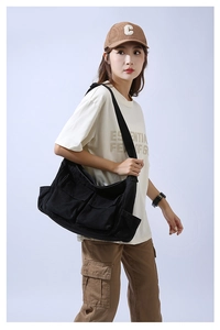 Detail view of large capacity black canvas crossbody bag showing pockets and shoulder strap