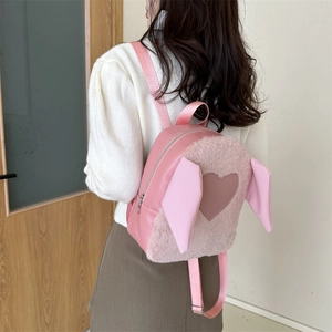 Detail view of pink plush rabbit ear backpack with heart patch on model back