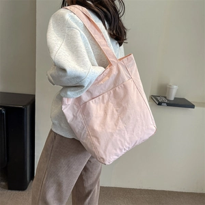 Detail view of a pink lightweight fabric tote bag with a functional front pocket and soft straps