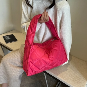 Detail of fuchsia quilted shoulder bag with soft padding and glossy nylon texture