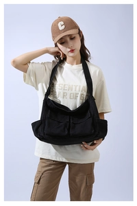 Detailed view of large black canvas messenger bag featuring vintage utility pockets