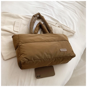 Détail du sac fourre-tout matelassé marron foncé montrant la texture en nylon et le logo