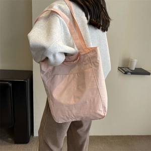 Detail view of pink nylon tote bag with pleated texture and functional front pocket
