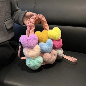 Détail d'un sac à main rose en peluche avec cœurs colorés et poignée à volants
