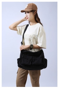 Detailed view of black canvas crossbody bag with multiple pockets and utility straps
