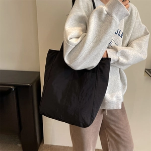 Close-up of a large black tote bag featuring crinkled fabric and vertical stitching