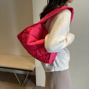 Detail of hot pink quilted nylon tote bag with padded texture and wide shoulder strap