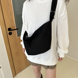 Détail du sac bandoulière minimaliste en toile noire avec une large bandoulière