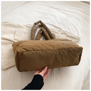 Détail d'un sac cabas matelassé marron avec texture moelleuse et écusson en cuir mode