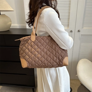 Détail de la texture nylon matelassée marron avec anses en cuir kaki clair et zip métallique