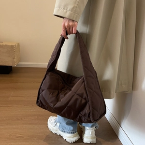 Detail of dark brown quilted nylon shoulder bag showing puffy texture and wide strap