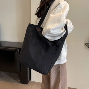 Detail of a large black tote bag featuring double straps for versatile shoulder or hand carry
