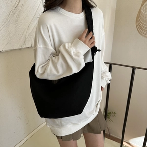 Sac hobo minimaliste en toile noire avec large bandoulière porté par un mannequin en studio