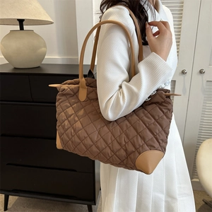 Grand sac cabas marron matelassé avec poignées en cuir, porté par un mannequin chic