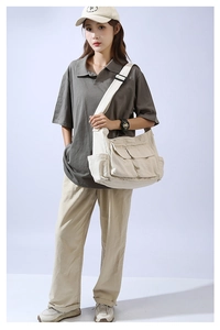 Detail view of cream canvas messenger bag featuring large utility pockets and wide strap