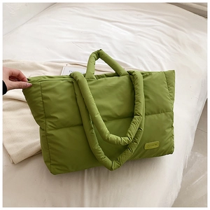 Gros plan du sac cabas matelassé vert montrant l'étiquette mode et le tissu rembourré