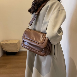Detail view of brown leather crossbody bag with adjustable wide strap and silver buckle