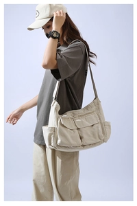 Detail showing the large capacity beige canvas bag with functional front utility pockets