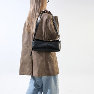 Borsa a tracolla minimalista in pelle PU nera indossata su blazer marrone e jeans