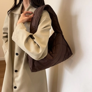 Close-up of a brown quilted puffer shoulder bag in shiny nylon with a large diamond pattern