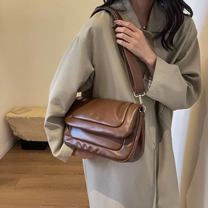 Detail of a dark brown PU leather shoulder bag featuring a padded texture and wide strap