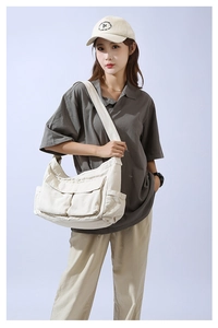 Close-up of off-white canvas crossbody bag with multi-pocket design on female model