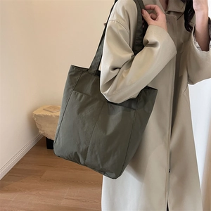 Detail view of dark olive nylon tote bag with functional front pockets and soft texture