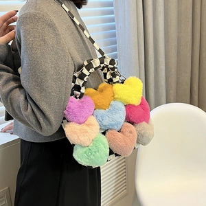 Détail d'un sac en peluche coloré en forme de cœur avec bandoulière à damier noir