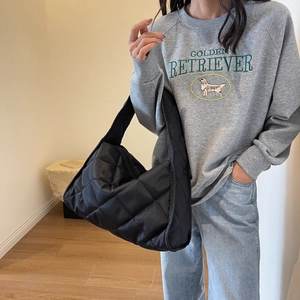 Side view of a quilted black tote bag on a model featuring soft nylon fabric design