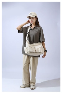 Off-white canvas messenger bag with multi-pocket design styled on a casual model