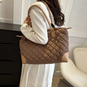 Gros plan du sac fourre-tout en nylon matelassé marron avec coins et poignées en cuir chic